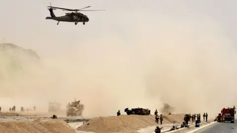 Getty Images A US black hawk helicopter flies over the site of a Taliban suicide attack in Kandahar