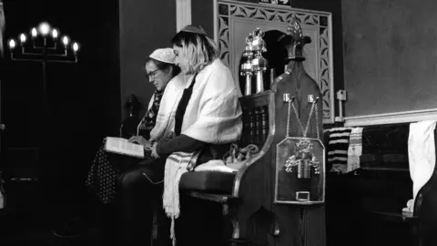 Nudrat Afzah Two women seated in the synagogue