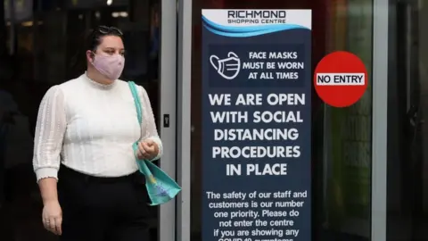 PA Media A woman walking out of a shop