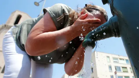 Reuters A woman cools off in a water fountain in Marseille as a heatwave hits France in June