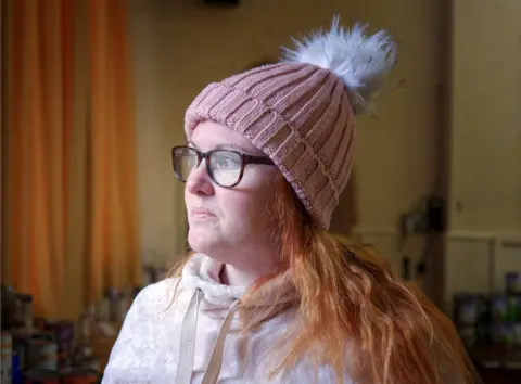 Laurence Cawley/BBC Mrs Tierney shown side on wearing a pink bobble hat
