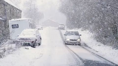 PA Media Cars drive through the snow in Gunnerside, North Yorkshire, on Sunday