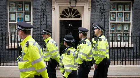 PA Media A group of police officers walk in front of Number Ten