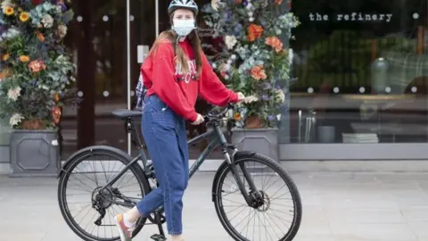 PA Media A cyclist wearing a facemask in Edinburgh