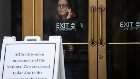 AFP A US government employee talks on the phone as she looks out of a closed Smithsonian museum in Washington, DC on January 18, 2019