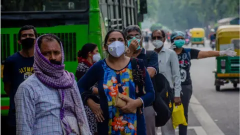 Getty Images Indian commuters wearing face masks wait for public transport on July 09, 2020 in New Delhi, India.