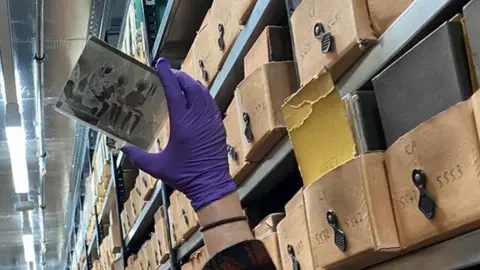 A gloved hand holds up a glass plate