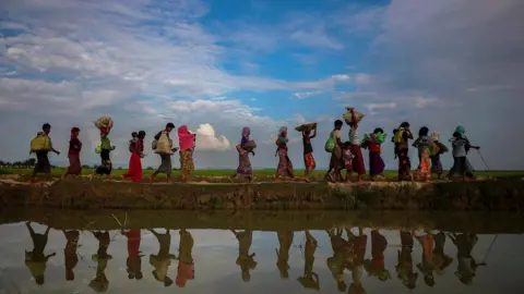 Reuters Rohingya refugees walking along a lakeside in Bangladesh