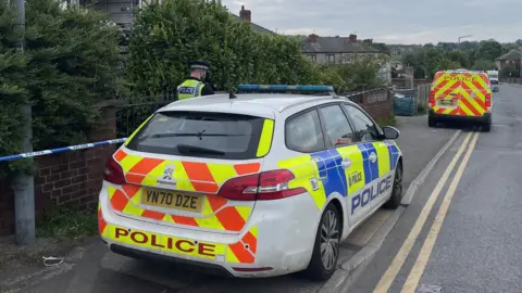 BBC/Simon Thake Police cars outside the house