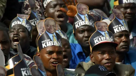 AFP Kenyans wearing Mwai Kibaki's hats gather for the swearing in ceremony of newly elected president Mwai Kibaki in Nairobi 30 December 2002