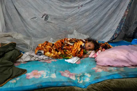 Encarni Pindado A baby lies in a makeshift shelter by a highway on the outskirts of San Pedro Sula