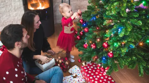 Getty Images Family decorating a tree