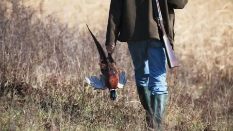 Getty Images A hunter carrying a pheasant