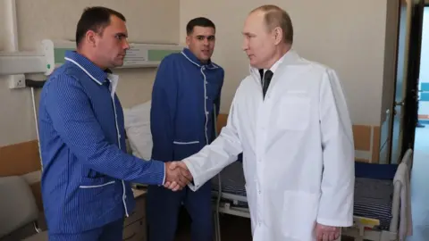 MIKHAIL METZEL/KREMLIN POOL/SPUTNIK Russian President Vladimir Putin (R) meets with Russian servicemen wounded during the Russian "special military operation" in Ukraine as he visits a Mandryk Central Military Clinical Hospital in Moscow, Russia, 25 May 2022