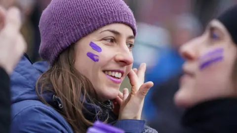 Getty Images A woman paints purple stripes on her face during a feminist women's bicycle protest on International Women's Day on March 08, 2020 in Berlin, Germany