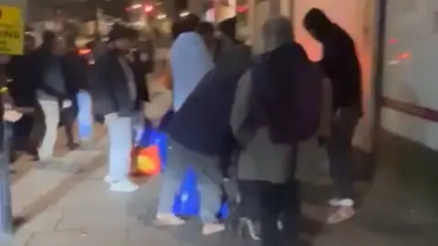 Danial Abbas The group of migrants pictured waiting for taxis to take them to Norwich after being left stranded in London