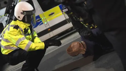 Getty Images A protester is placed in a spit hood as he is restrained by police during a Black Lives Matter protest in London in June 2020