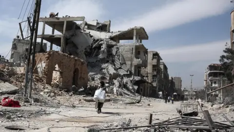 AFP People carry their belongings as they leave the town of Hamouria in the Eastern Ghouta (15 March 2018)