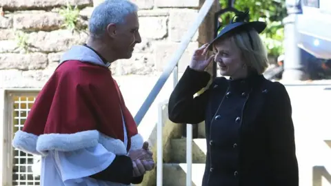 Getty Images Britain's Prime Minister Liz Truss is greeted by Dean of Llandaff Cathedral Michael Komor upon her arrival for a Service of Prayer and Reflection for the life of Queen Elizabeth II