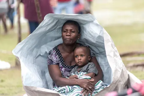 Reginald Louissaint / AFP People gather after spending the night outside after facing the severe inclement weather of Tropical Storm Grace near Les Cayes, Haiti, on 17 August 2021