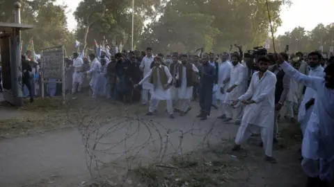 EPA Protestors react after police fired tear gas shells to stop them reaching the French embassy in Islamabad