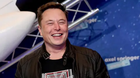 Getty Images Elon Musk with picture of space rocket behind him