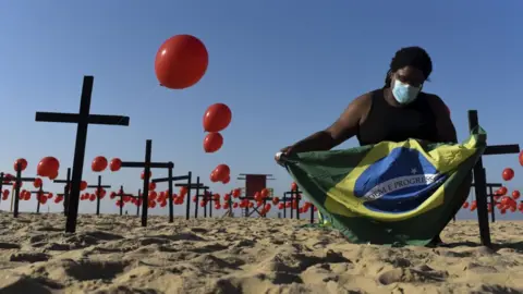 Anadolu Agency/Getty A man holds Brazilian flag between red balloons in Rio de Janeiro