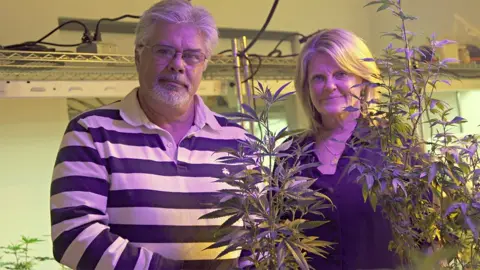 BBC Jayne and Vic Grissom pose in their marijuana plant display room