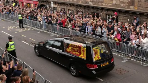 PA Media The coffin is driven down the Royal Mile in Edinburgh