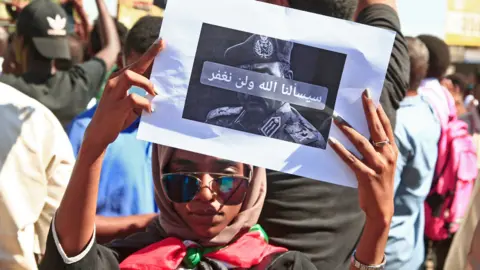 AFP A Sudanese protester lifts a placard during a demonstration calling for a return to civilian rule in the capital Khartoum, on 21 November 2021