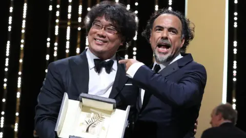 AFP South Korean director Bong Joon-Ho (L) poses on stage with Mexican director and President of the Jury of the Cannes Film Festival Alejandro Gonzalez Inarritu after he was awarded with the Palme d"Or for the film "Parasite" on May 25, 2019