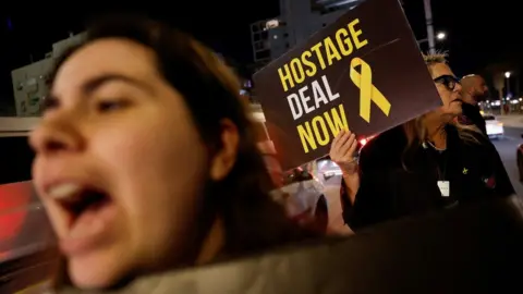 Reuters A woman holds up a sign saying "Hostage deal now" at a demonstration in Tel Aviv, Israel, demanding that the government negotiate the release of Israeli hostages held by Hamas in the Gaza Strip (5 March 2024)