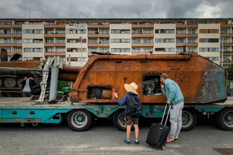 MARTIN DIVISEK/EPA-EFE/REX/Shutterstock A man with a child looks at a Russian military equipment which was destroyed in fights with the Ukrainian army, placed for exhibition on a truck, in Prague, Czech Republic, on 10 July 2022