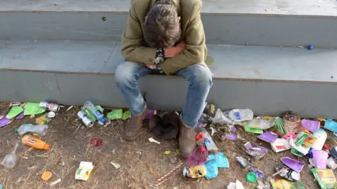 PA Man sitting among rubbish