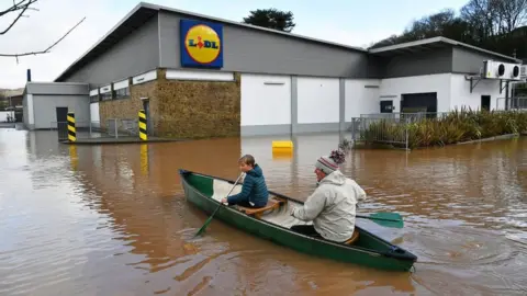 Ben Birchall | PA Wire Two people in canoe rowing by a Lidl store in Monmouth