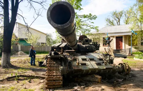 Getty Images Local residents look at a destroyed Russian tank in Sloboda, Chernihiv, Ukraine - 8 May 2022