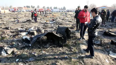 EPA Iranian emergency services personnel inspect the wreckage of Ukraine International Airlines flight PS752 near Tehran (8 January 2020)