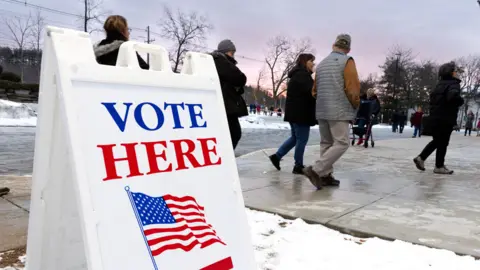 Voters wait in line to get a ballot and vote in the New Hampshire primary, at a voting site at Pinkerton Academy in Derry, New Hampshire, USA, on 23 January 2024