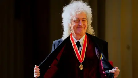 PA Media Brian May smiles to the camera after being knighted