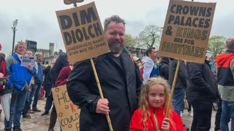 A man and his daughter holding placards