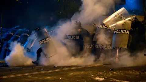 Getty Images Riot police are surrounded by smoke during clashes in Lima on 14 November 2020