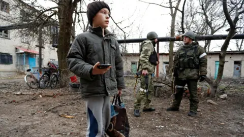 Reuters Boy outside damaged apartment block