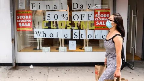 Getty Images A person walks by a going out of business sign displayed outside a retail store in New York City