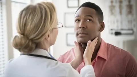 Getty Images Doctor examining throat of patient