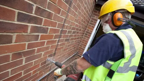 Getty Images A man installing cavity wall insulation
