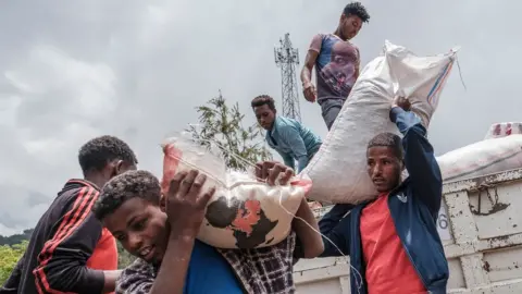 Getty Images Civilians displaced by fighting in northern Ethiopia offloading food and supplies from a truck at a school in Dessie, Ethiopia, on August 23, 2021