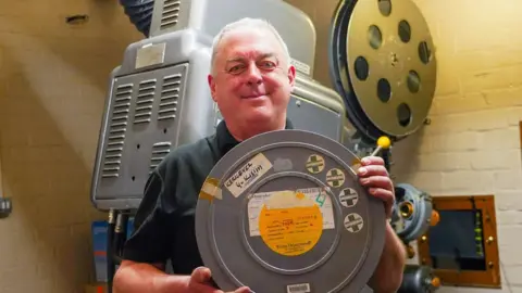 Oli Constable/BBC Rob Younger holding a tin of the film