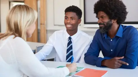 Getty Images Parent and child talking to a teacher