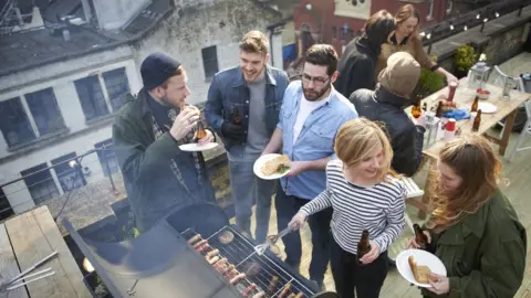 Getty Images Young people enjoy a barbecue on a rooftop