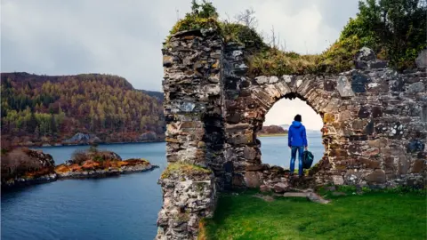 Getty Images Female tourist at the ruins of Strome Castle on the shores of Loch Carron